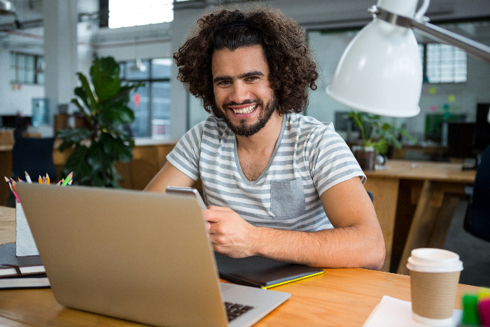 Professor sorrindo enquanto avalia projetos em laptop