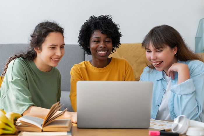 Alunas colaborando em laptop com entusiasmo